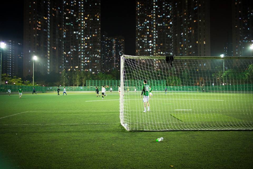 Pemain menendang bola di malam hari di bawah lampu sorot